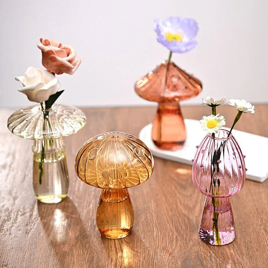 Petits vases champignon en verre coloré avec des fleurs sur une table en bois