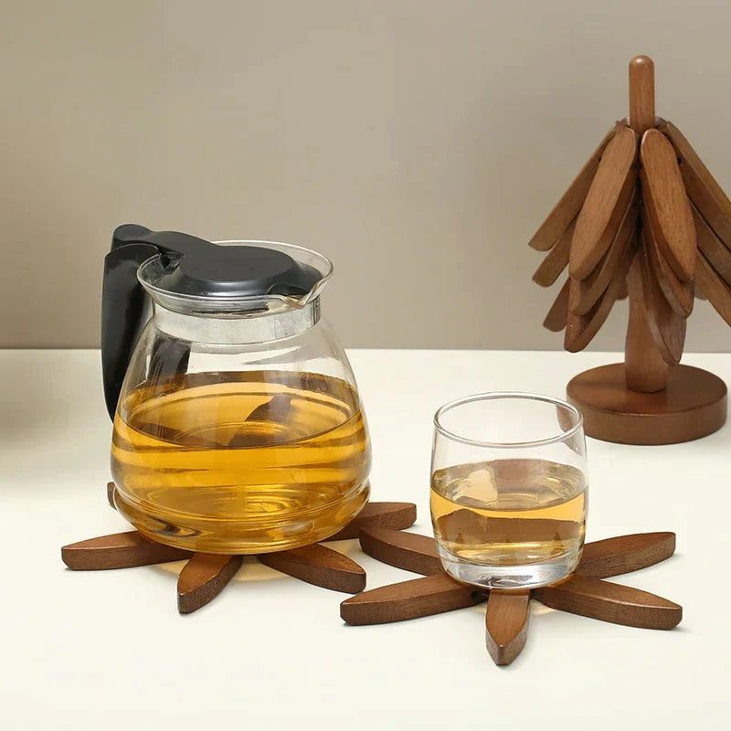 Théière en verre sur un dessous de plat en bois, à côté du sapin en bois